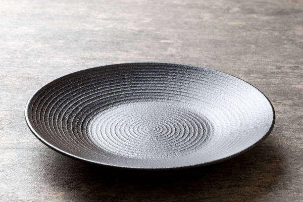 Perspective view of empty black plate on cement background. Empty space for your design