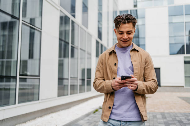 istock Cheerful Young Man Texting On His Smartphone Outdoors 1499956931