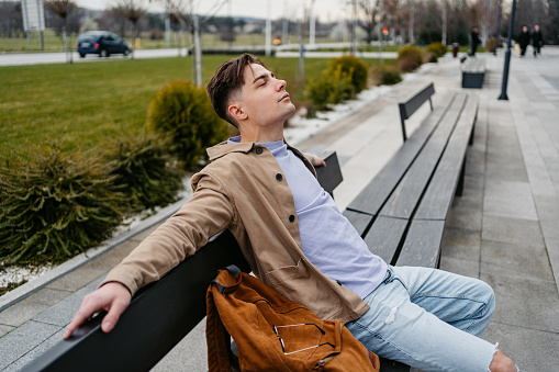 Young man relaxing on the city bench.