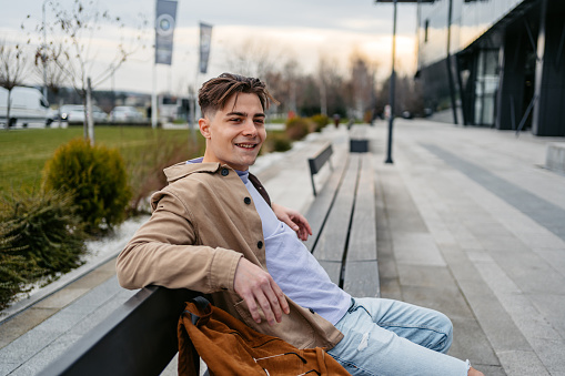 Young man relaxing on the city bench.