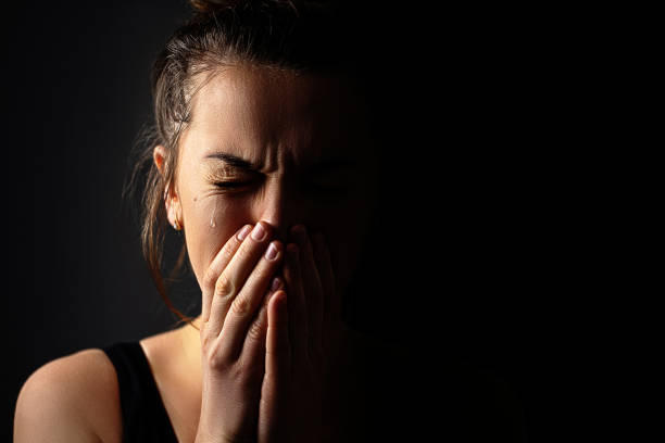 istock Sad grieving crying female with folded hands and tears eyes on a dark black background during trouble, life difficulties, loss and emotional problems. Copy space 1499958034