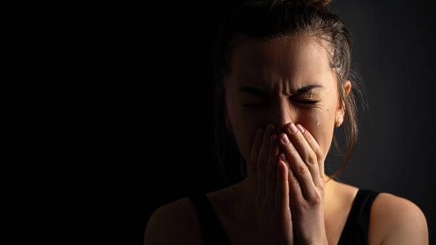 istock Sad desperate grieving crying woman with folded hands and tears eyes on a dark black background during trouble, life difficulties, loss and emotional problems. Copy space 1499958042