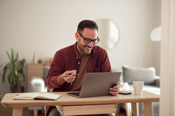 istock Smiling man talking to someone over the laptop, having a conversation. 1499958698
