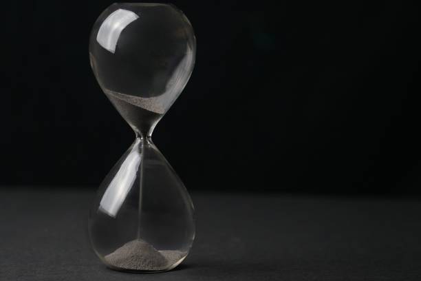 istock Hourglass with sand falling through, set against a black backdrop, the concept of time passing 1499958839