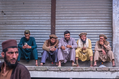 Islamabad, Pakistan - March 30, 2023 : Unidentified men sitting and talking at the roadside.