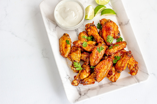 Baked Chicken Wings Garnished with Cilantro Top Down Photo on White Background