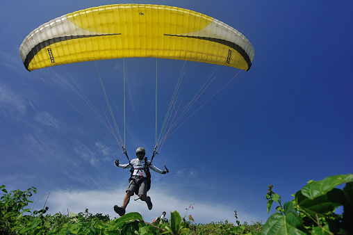 August 6, 2021 - Ager, Spain: profesional Paraglider pilot running and jumping taking off from the mountain while other people are looking at him