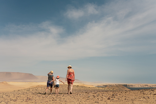 Two mothers with their daughter walking in the desert