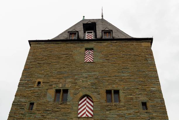 A grand and elaborate building facade with a clock tower adorning the top and multiple flags painted on the exterior walls