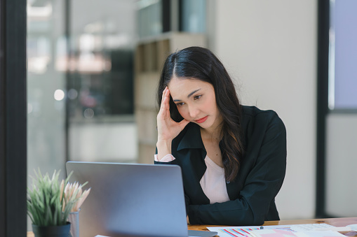 Young Indian Accountant Woman in casuals working on financial analysis documents with a tense expression in the office. Business finance and accounting concepts