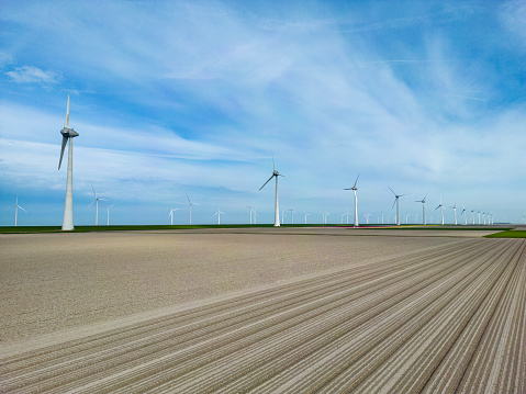Ploughed dry agriculture field as a result of long time drought, in the background wind turbines.
