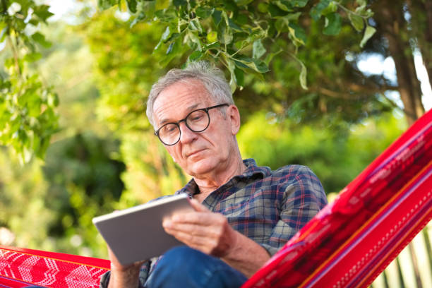 istock Senior man wearing eyeglasses sitting on hammock 1499970542