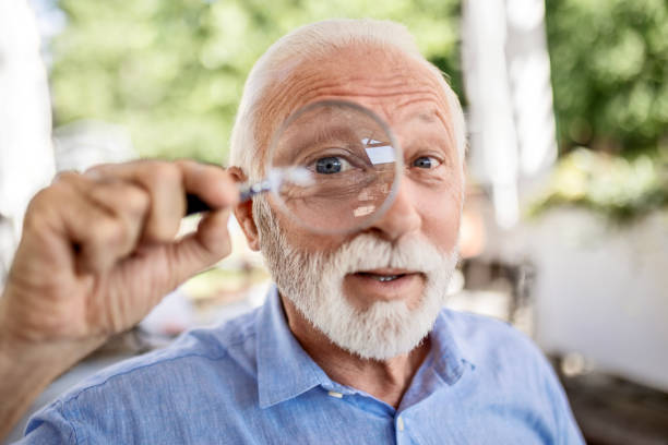 istock Funny senior man with magnifying glass looking at camera 1499970939