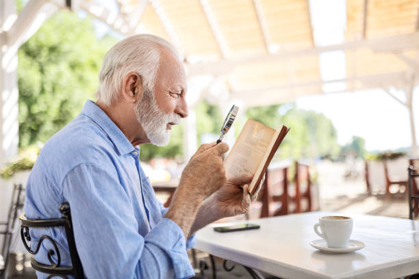 istock Elderly man with magnifying glass in hand reading book 1499970986