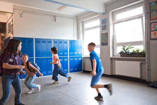 Happy kids running during break in the school corridor.