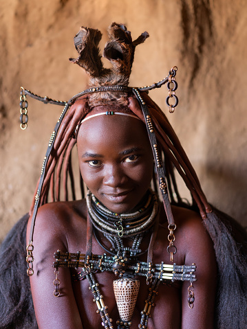 Young Himba woman wearing traditional jewelry at her village in Namibia, Africa.