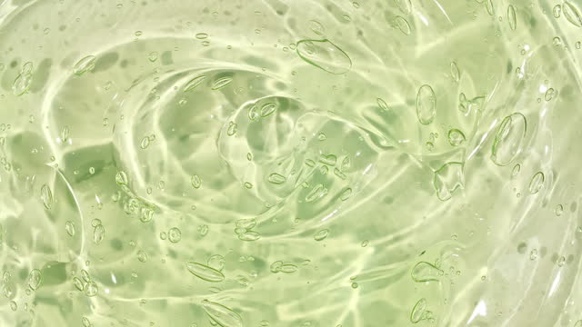 Transparent liquid gel background, clear serum texture. Motion, rotation of the beauty skincare product sample with bubbles. Top view. Macro Shot.