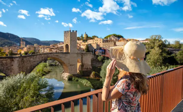 Tour tourism in Catalonia,  Woman taking photography with smartphone of Besalu village in Spain