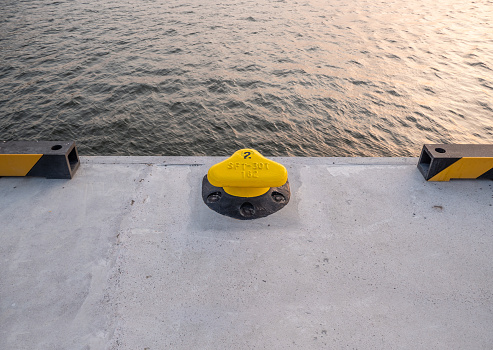 A yellow cleat on a concrete bank.