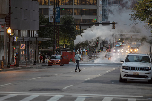 Baltimore, Maryland - October 03, 2019: Traffic in Baltimore, Maryland. USA. Hot Water Steam in Background. Downtown Street