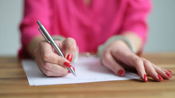 istock Female hands in metal handcuffs writing explanatory note closeup 1499989068
