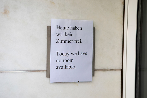 Homemade sign taped to the wall outside a hotel building in Cologne, Germany. Written in German and English