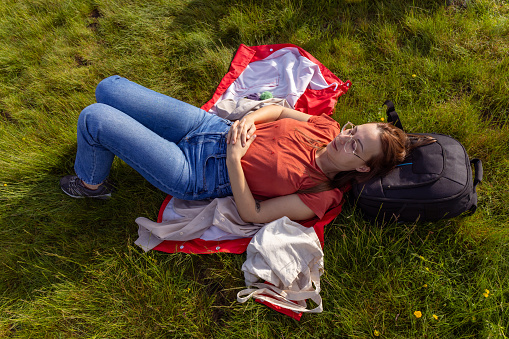 Young woman smiling while lying down on the grass in the public park