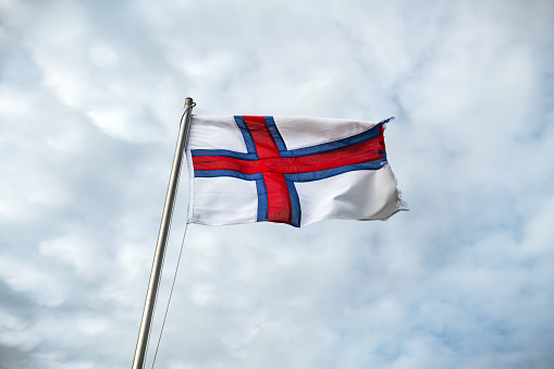 Flag of Faroe islands waving against a cloudy sky