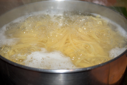 noodles cooking in a pot of boiling water with burning foam almost ready to take out