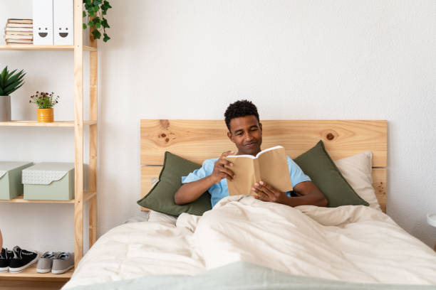 istock Man enjoying a book in bed on sunday. 1499996188