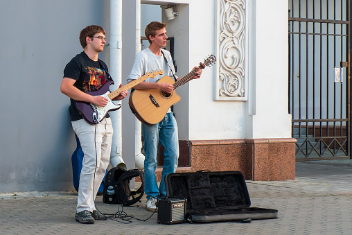 Minsk, Belarus - August 8, 2017: Street musicians. Two guys playing guitars on a city street