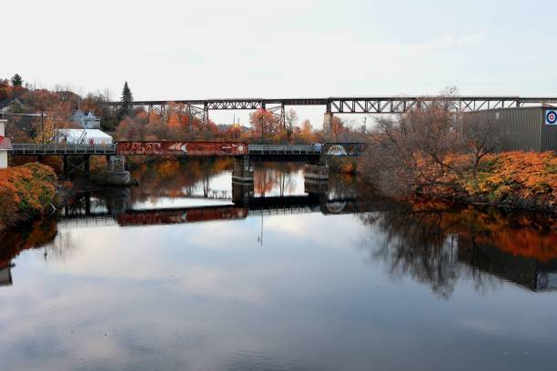 istock Steel bridge arches over a river surrounded by lush autumn trees 1499999060