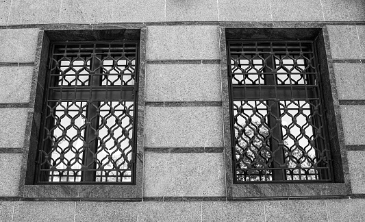 2 windows with metal bars. Two windows closed with bars, metal shutters.