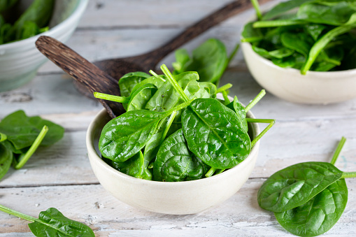 Fresh baby spinach leaves - wooden background