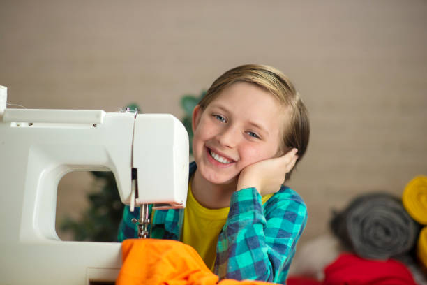 istock handsome boy sewing clothes on a sewing machine at home 1500010801