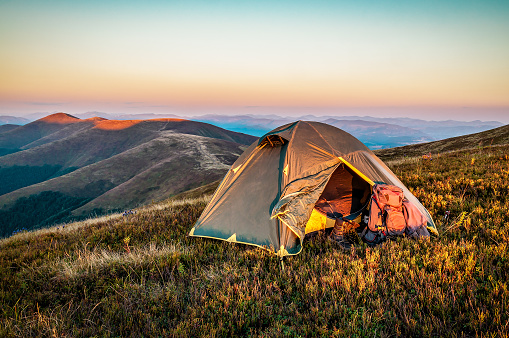 Tourist tent in Mountains at beautiful sunrise or sunset