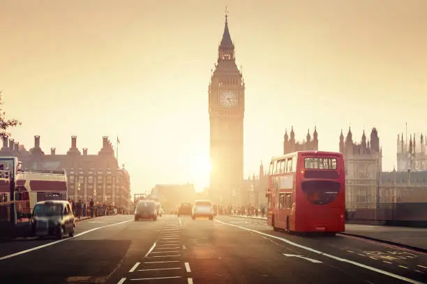 Beautiful sunset over London city. Big Ben tower, red London bus and the Westminster Abby - the symbols of London.