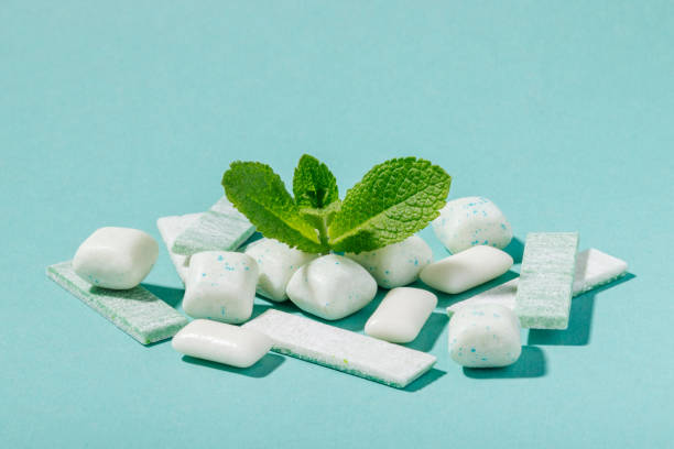 A bunch of mint chewing gum and fresh mint leaves on a blue background A bunch of mint chewing gum and fresh mint leaves on a blue background Breath Mints or Gum stock pictures, royalty-free photos & images