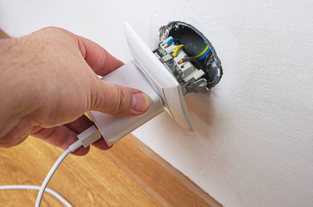 istock Person hold white USB mobile phone charger plugged into a broken power outlet. 1500017576