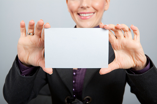 Young business girl in office holding blank card