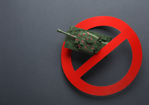 Stop the war Toy military tank with a prohibition sign on gray background