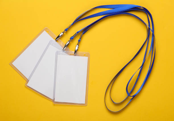istock Empty white ID card badges mockup with blue belt on yellow background. Staff identity name tag. Space for text and design. Top view. Flat lay 1500021590