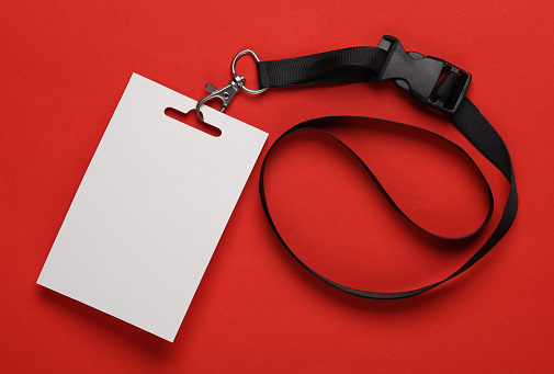 Empty white ID card badge mockup with black belt on red background. Staff identity name tag. Space for text and design. Top view. Flat lay
