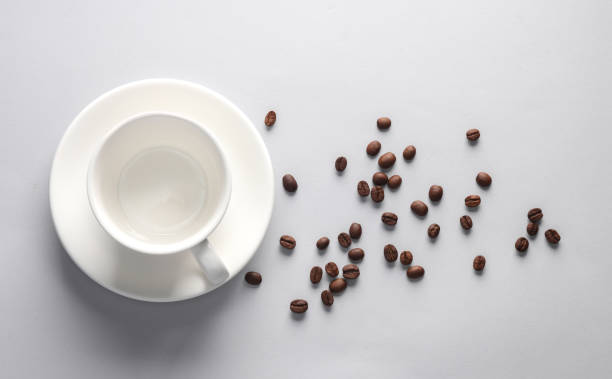 istock Ceramic coffee cup with coffee beans on gray background. Top view 1500021762