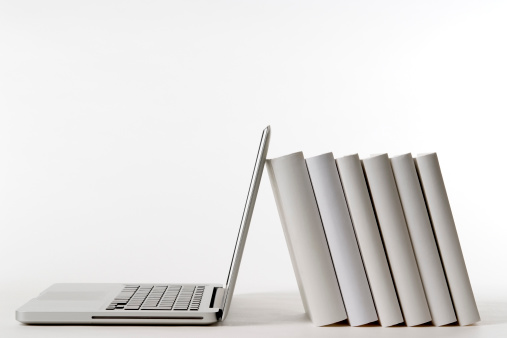 Laptop leaning white blank books on white background.