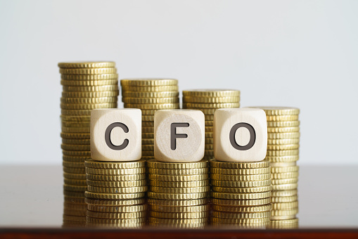 CFO text on wooden cubes standing on coin towers. CFO. business concept