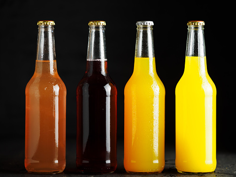 citrus lemonades or sodas in glass bottles on a dark background