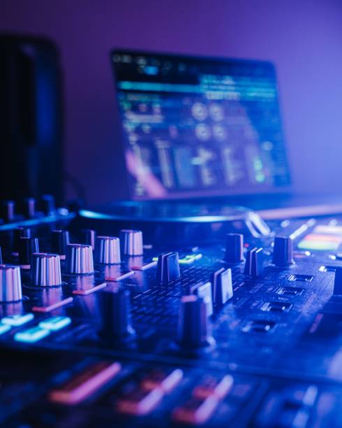 istock Professional audio mixing board connected to a laptop, displaying the various knobs and buttons. 1500032301