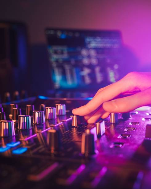 istock Professional audio mixing board connected to a laptop, displaying the various knobs and buttons. 1500032303