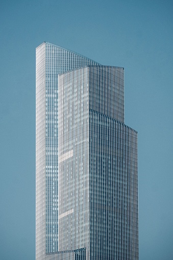 An impressive high-rise building with a modern, transparent glass facade stands prominently in the city skyline